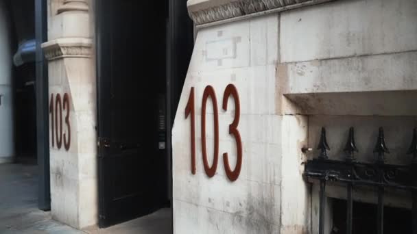 Address number 103 on a marble-looking building next to the entrance — Wideo stockowe