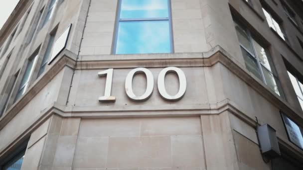 Address number 100 under a window on the corner of a gray building — Αρχείο Βίντεο