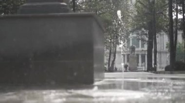 Arka planda ağaçlar olan bir çeşmede akan sular.