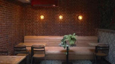 Tables, chairs, and three lights on a red brick wall from a vegan restaurant