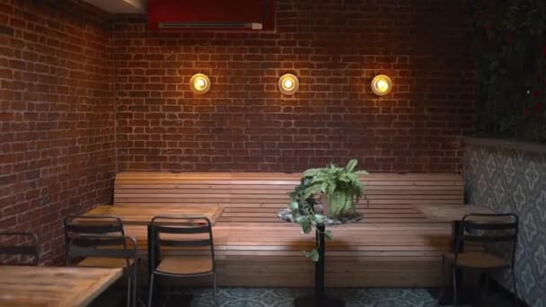 Tables, chairs, and three lights on a red brick wall from a vegan restaurant — Stock Video