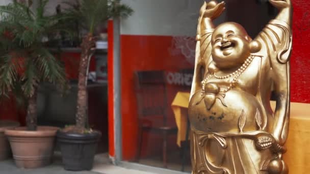 Närbild av en gyllene glad Buddha staty utanför ett fönster — Stockvideo