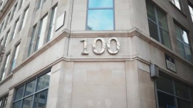 Gri bir binanın köşesindeki pencerenin altında 100 numaralı adres.