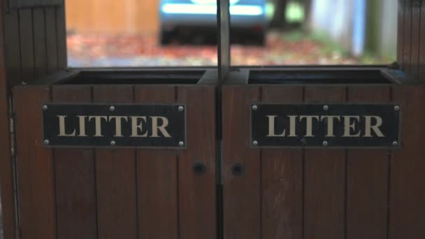 Vue rapprochée de deux poubelles en bois avec une voiture floue comme arrière-plan — Video