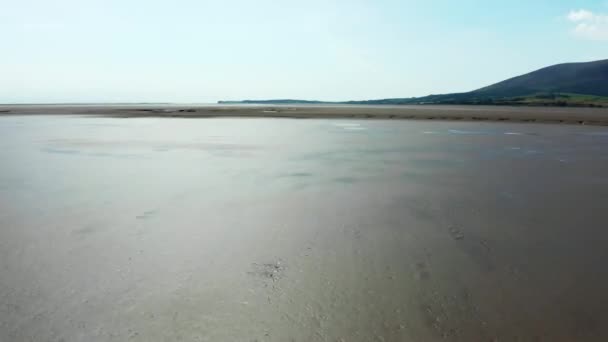 Vista aérea para a frente de uma terra molhada da areia com uma montanha na distância — Vídeo de Stock