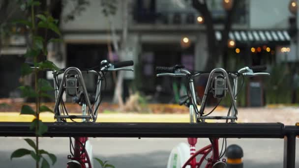 Dvě veřejná kola zaparkovaná na ulici s rozmazané budovy jako pozadí — Stock video