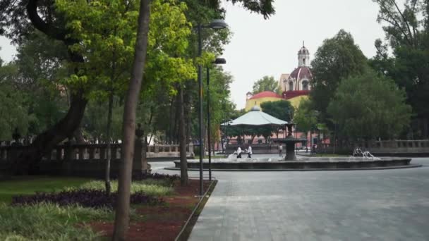 Fuente redonda en medio de un parque con gente caminando — Vídeos de Stock