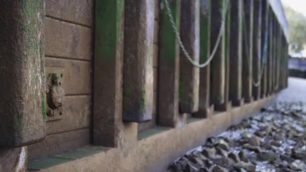 Uma parede de concreto acorrentado parcialmente coberto por Moss ao lado de um solo rochoso — Vídeo de Stock