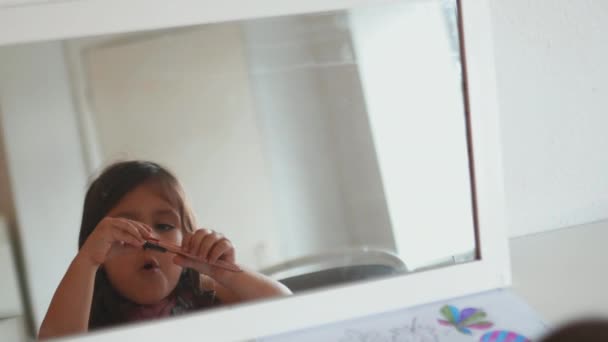 Specchio che riflette l'interno di una stanza e una bambina che gioca con una penna — Video Stock