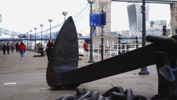 Big black anchor on the thoroughfare with people walking in the distance — Αρχείο Βίντεο