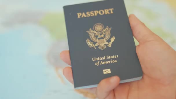 Hand Holds a United States of America Passport with a North American Map Behind — Vídeo de stock