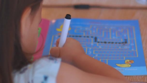 Little Girl Completing a Fun Maze on a Children Book with a Black Market — Vídeo de Stock