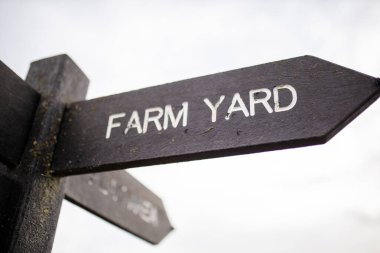 Wooden pole with indications pointing out the way to the farm yard