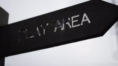 Wooden pole with indications pointing out the way to the play area