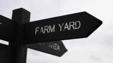 Wooden pole with indications pointing out the way to the farm yard