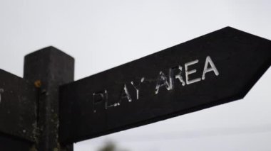 Wooden pole with indications pointing out the way to the play area