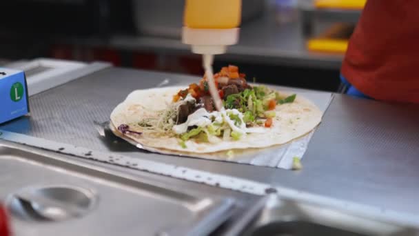 Muž v modrých rukavicích přidává smetanu na rozbalené burrito — Stock video