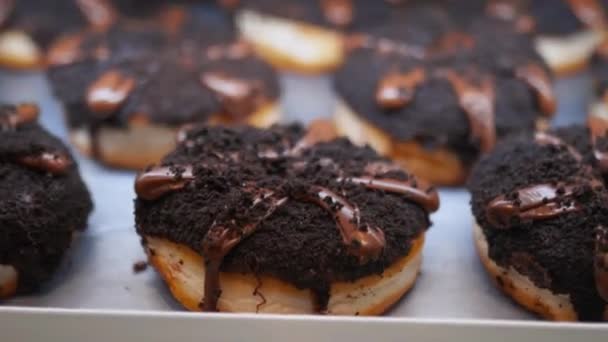 बेकरीमध्ये चॉकलेटमध्ये मोठ्या प्रमाणात झाकलेले डुगनट्सचे दृश्य बंद करा — स्टॉक व्हिडिओ