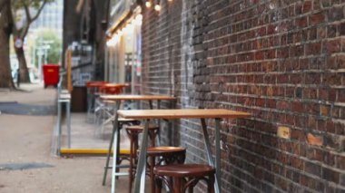 Tables and chairs next to a red bricks wall with the street as background