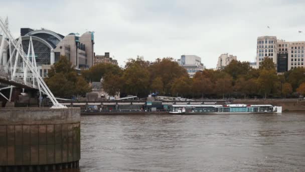 River Thames with autumn-colored trees on the other side and under a cloudy sky — Vídeo de Stock