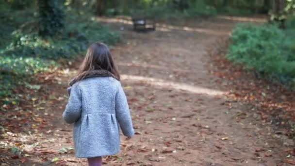 Niña caminando junto a su madre en un camino de tierra rodeado de bosques — Vídeos de Stock