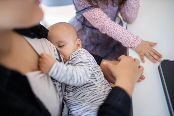 Slapende baby rustend in de armen van haar moeder terwijl ze aan haar shirt trekt — Stockfoto