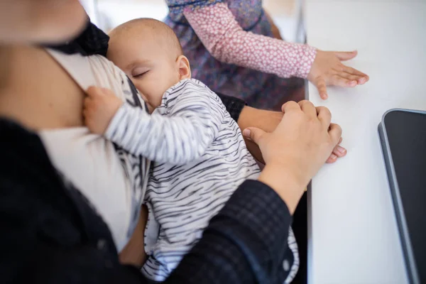 Slapende baby rustend in de armen van haar moeder terwijl ze aan haar shirt trekt — Stockfoto