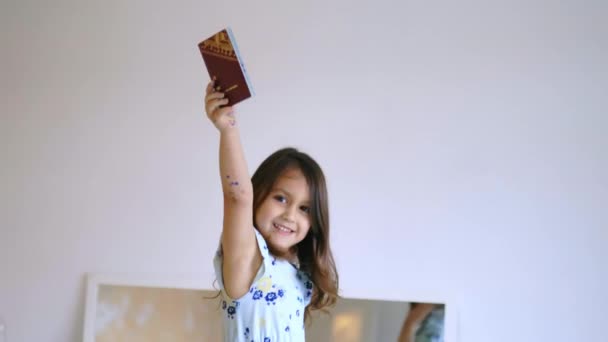 Szczęśliwa dziewczynka na krześle podnosząca szwedzki paszport wysoko ponad głowę — Wideo stockowe
