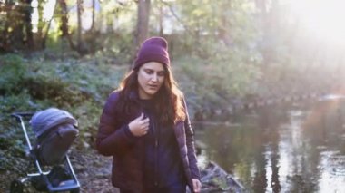 Güzel bir kadının üzerindeki güneş ışığı Ormandaki bir nehrin yanında gülümsüyor ve davet ediyor