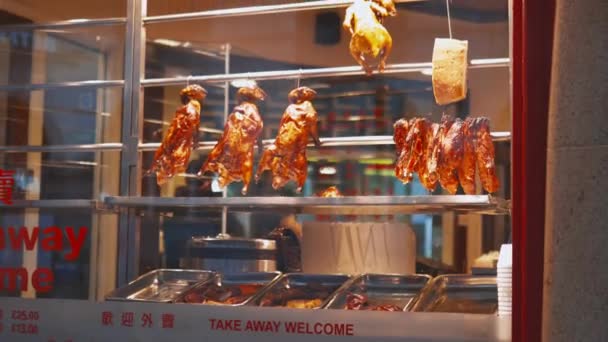 Gebratenes Fleisch hängt hinter dem Fenster eines chinesischen Restaurants — Stockvideo