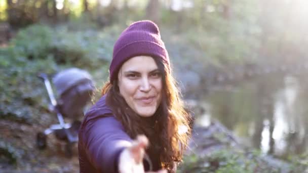 Raio de sol acima da bela mulher sorrindo e convidando ao lado de um rio na floresta — Vídeo de Stock