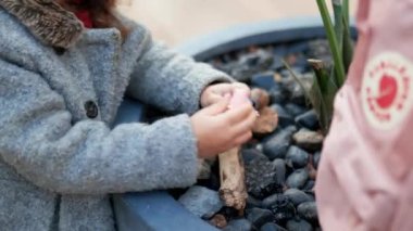 Küçük kız sakince oyuncaklarla oynuyor kayalarla dolu bir saksıda