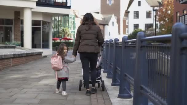 Niña con una mochila rosa y su madre caminando tranquilamente de la mano — Vídeo de stock