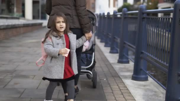 Niña con una mochila rosa y su madre caminando tranquilamente de la mano — Vídeo de stock