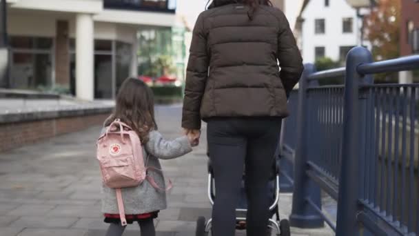 Rózsaszín hátizsákos kislány és az anyja nyugodtan sétálnak kéz a kézben. — Stock videók