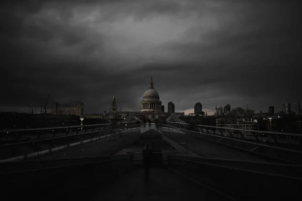 Millennium Bridge with the St Paul Cathedral in the distance below cloudy sky