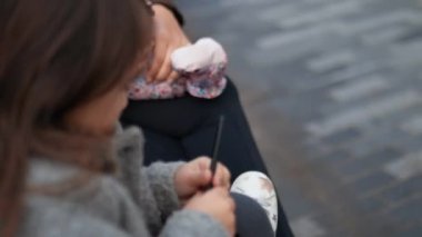 Tablete çubuk figürleri çizen konsantre küçük kız.
