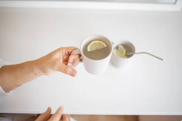 Рука держит чашку лимонного чая с ломтиком лимона внутри — стоковое фото