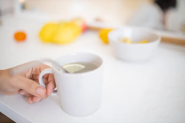 Рука держит чашку лимонного чая с соломой и ломтиком лимона — стоковое фото