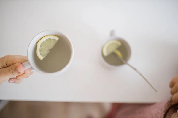 Hand holding a cup of lemon tea with a lemon slice inside — Stock Photo, Image