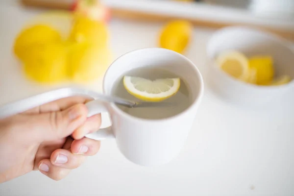 Рука держит чашку лимонного чая с соломой и ломтиком лимона — стоковое фото