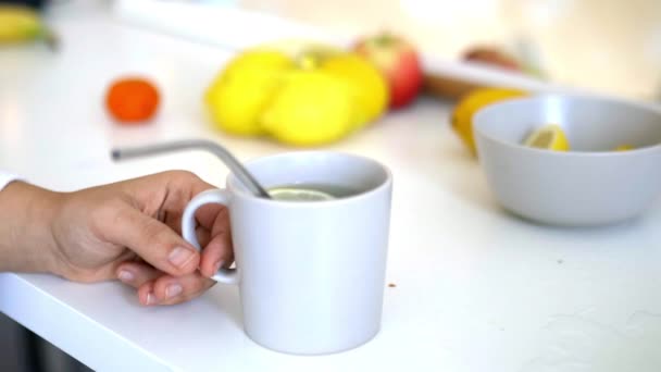 Main tenant une tasse de thé au citron avec une paille et une tranche de citron — Video