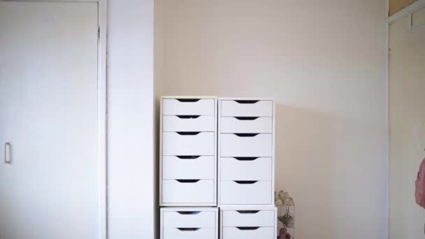 Beautiful woman walking to a white chest of drawers — Stock Video