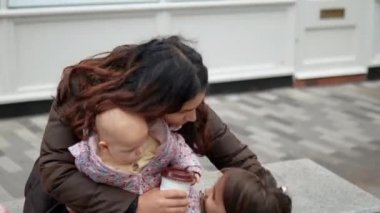 Mutlu anne gülümsüyor ve iki güzel kızına sarılıyor.