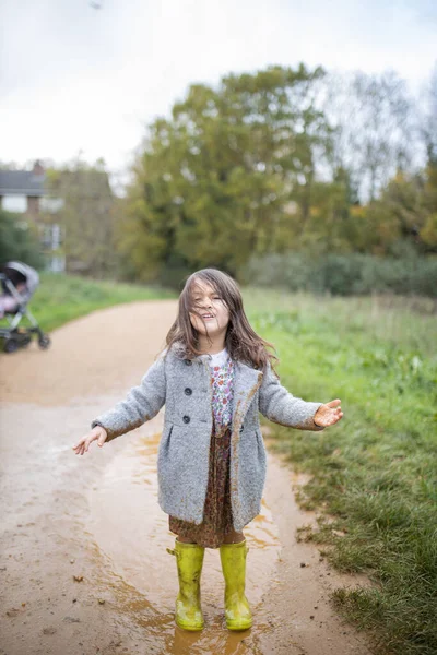 Glückliches kleines Mädchen lächelt hinreißend nach einem Sprung in eine schlammige Pfütze — Stockfoto