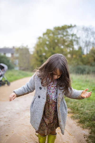 Kleines Mädchen blickt nach einem Sprung in eine Pfütze auf ihre schlammige Kleidung — Stockfoto