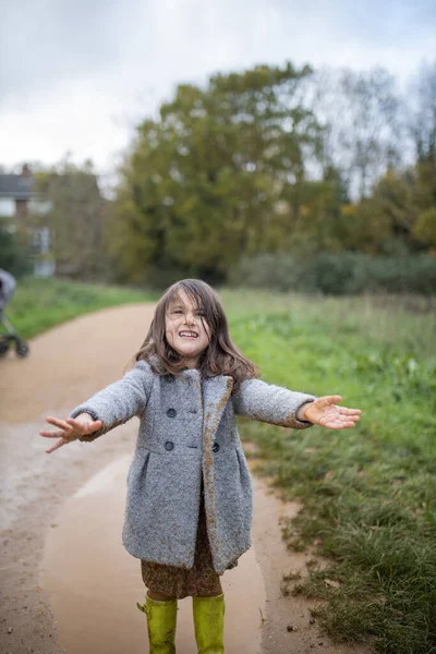 Glückliches kleines Mädchen lächelt hinreißend nach einem Sprung in eine schlammige Pfütze — Stockfoto