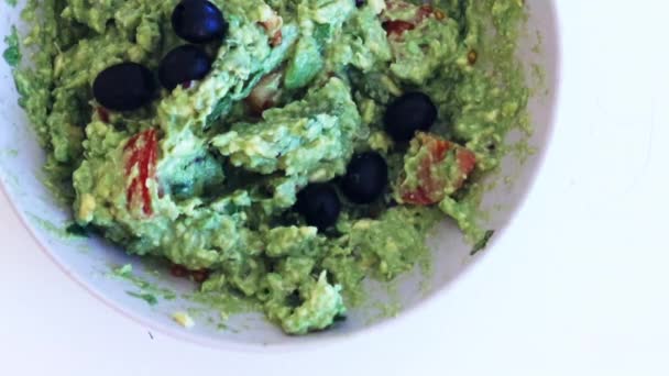 Vrouwelijke hand dompelen nacho 's in guacamole saus met olijven — Stockvideo