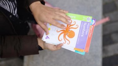 Anne renkli anaokulu kitaplarını karıştırıyor.