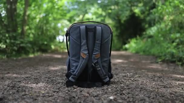 Gray backpack for photography equipment on a dirt path in a park — Stock Video